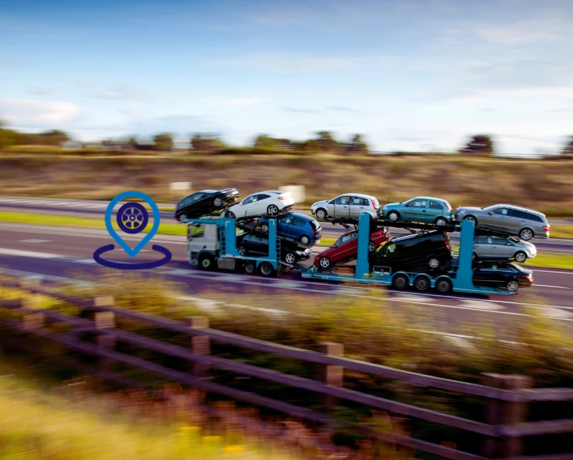 Car transporter loaded with vehicles on motorway with GPS tracking icon overlay