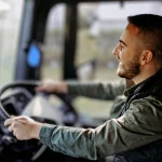 Smiling HGV driver at the wheel, demonstrating a driver-facing fleet CCTV system for behaviour monitoring
