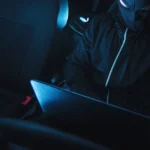 Masked car thief using a laptop for keyless theft
